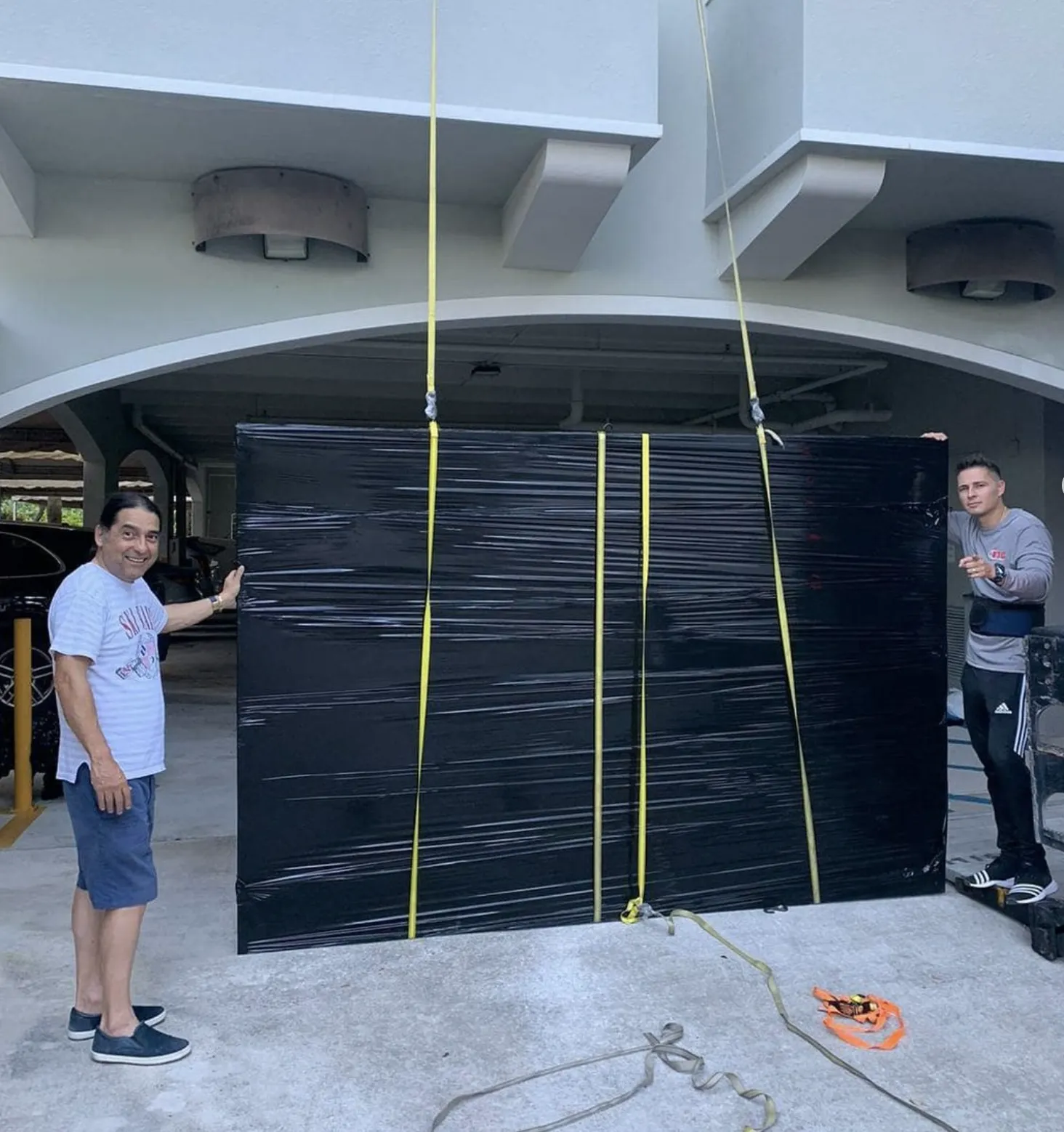 ETG movers guiding a large wrapped item being lifted
