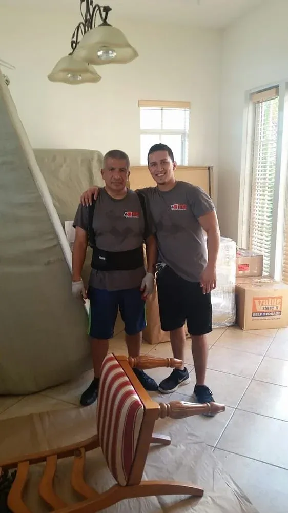 Two ETG movers in grey company shirts standing in a client apartment