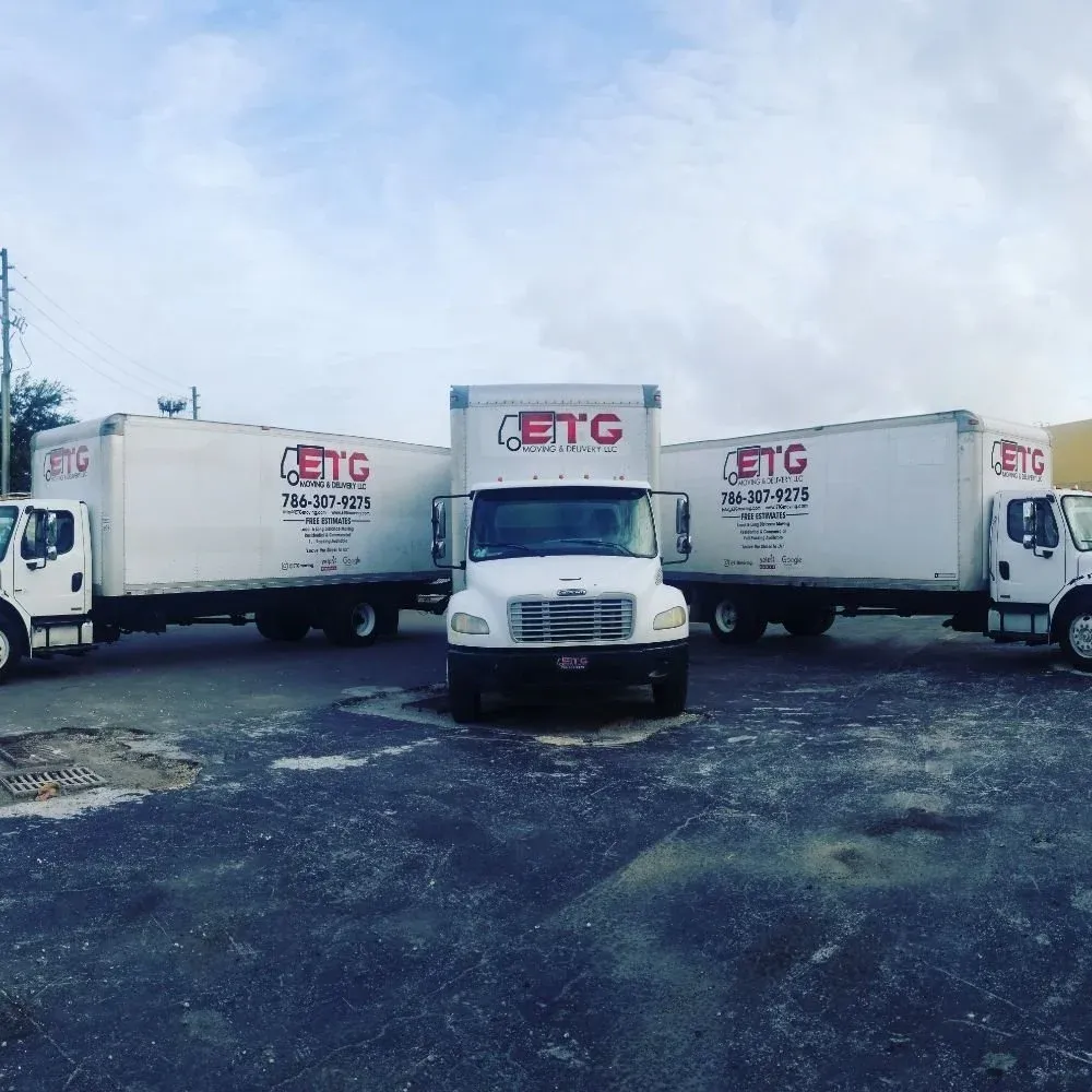 Three white ETG Moving & Delivery trucks parked together