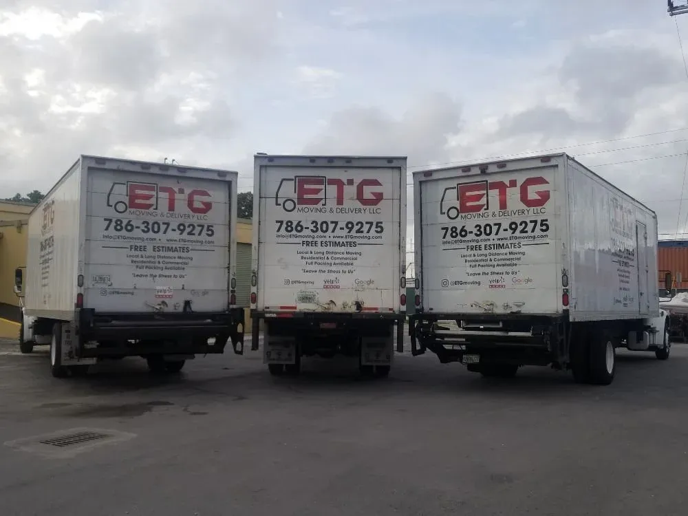 Three ETG Moving & Delivery trucks lined up with phone number on the back